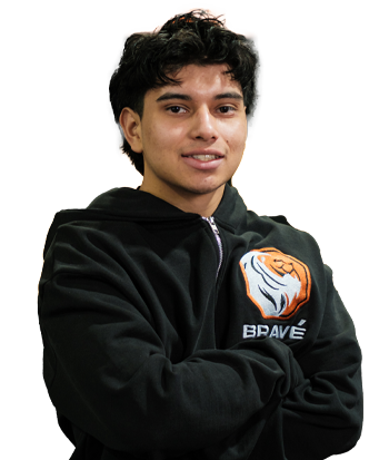 Deepak Kullar smiling confidently at esports event, wearing black hoodie with "Brave" logo, standing in front of a blurred background with orange and black colors.