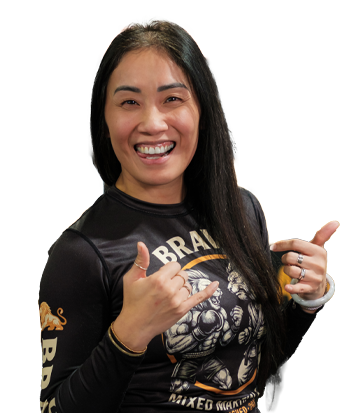 Woman smiling and giving thumbs up, wearing a black graphic t-shirt, in a lively indoor setting.